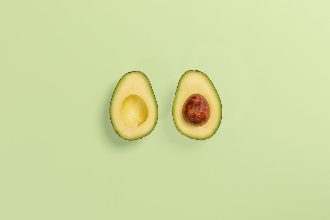 Two halves of a ripe avocado showing the flesh and pit