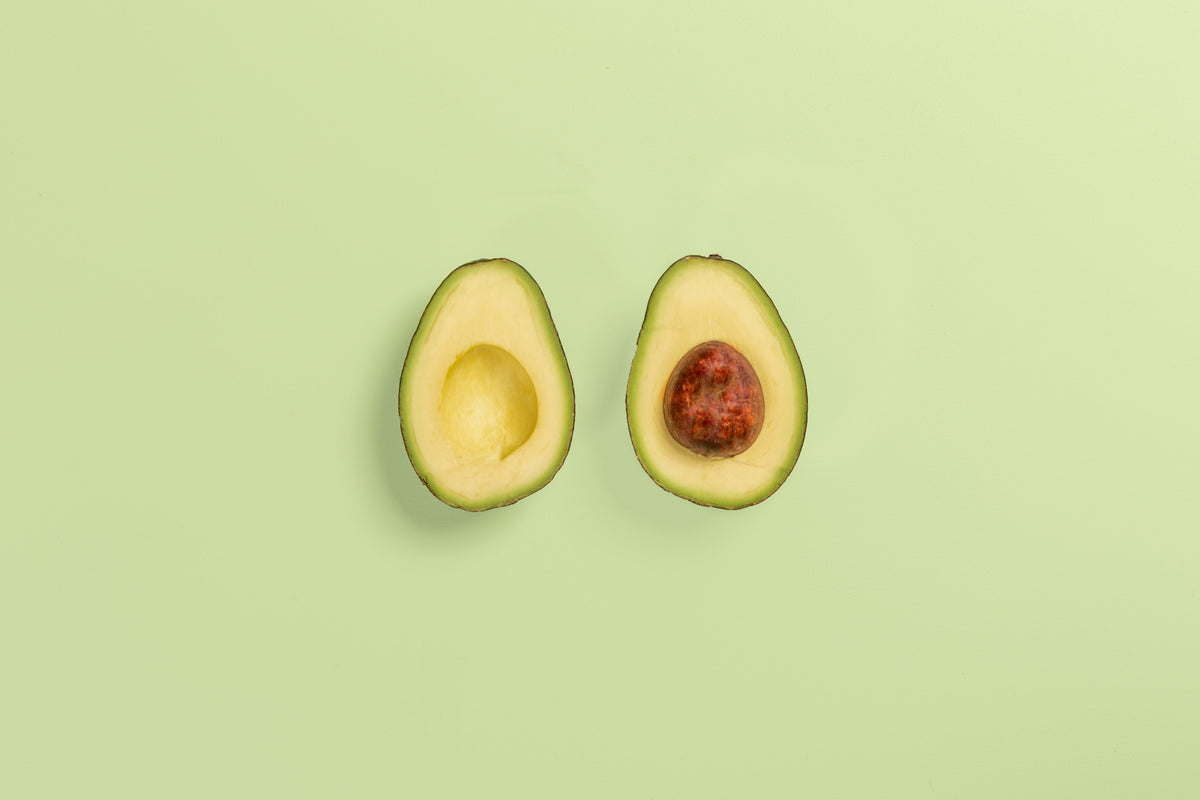 Two halves of a ripe avocado showing the flesh and pit